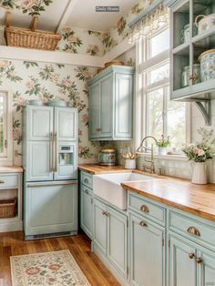 a kitchen with blue cabinets and floral wallpaper on the walls, along with wooden floors