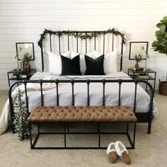 a bedroom with a metal bed frame, white sheets and brown footstools on the floor