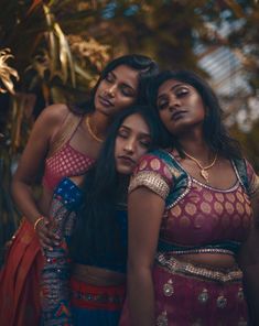 three women in sari standing next to each other with their arms around one another