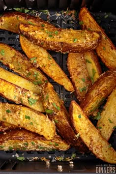 grilled potato wedges with parsley on top in an air frying pan