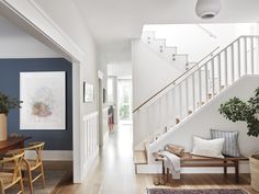 a living room filled with furniture and a wooden table next to a stair case on top of a hard wood floor