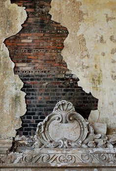 an old brick wall with a rose in front of it