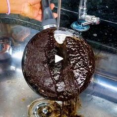 a person is washing a chocolate cake in a sink with water running down the drain