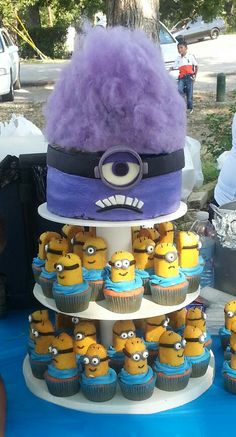 there is a tiered cake with cupcakes in the shape of minion's