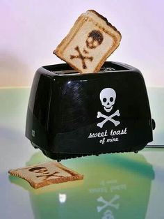 a toaster with a skull and crossbones on it sitting next to a slice of bread