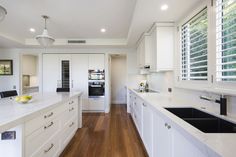 a large kitchen with white cabinets and wood flooring, along with an island in the middle