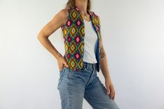 "Vintage tapestry wool vest  1960/70s Blue waistcoat with jacquard pattern in yellow, brown and pink colors . No closure. Straight cut , pointed front bottom. Woven item, handmade. Without label . Blue lining. Bohemian/hippie style. In very good condition. To note: (photos)  Tasks on the bottom of the lining.  Without composition and size label. Wool  Estimated size: XS/S The model wears usually a size S(EU 36/38) and measures 170cm / 66,9\" . Measures (flat):  Shoulder: 30cm - 11,8\" Chest: 37cm - 14,5\" Bottom: 35cm - 13,7\" Length: 52cm - 20,4\" Sleeve opening: 19cm - 7,4\" Please note that our items are vintage and may have slight imperfections. For more details, product information or additional photos, please do not hesitate to contact us." Bohemian Hippie Style, Blue Waistcoat, Vest Handmade, Tapestry Vest, Vintage Tapestry, Wool Vest, Jacquard Pattern, Bohemian Hippie, Front Bottoms