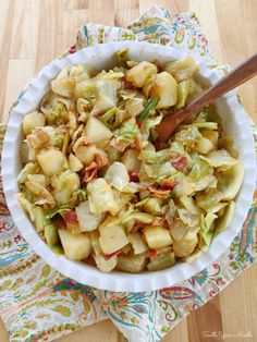 a white bowl filled with chopped vegetables on top of a wooden table next to a napkin