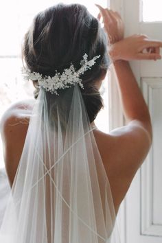 the back of a bride's head wearing a veil with flowers and pearls on it