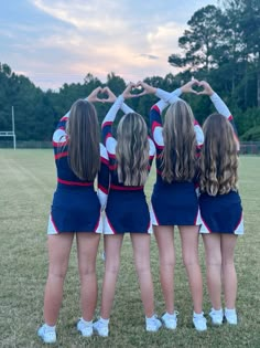 three cheerleaders standing in the middle of a circle making a heart shape with their hands