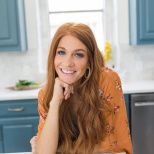 a woman sitting at a kitchen table smiling