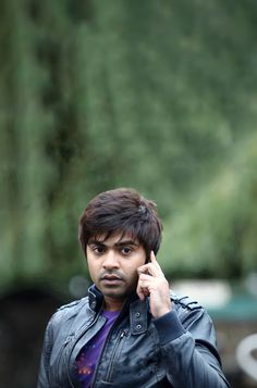 a man in a leather jacket talking on a cell phone