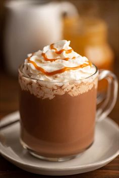 a close up of a cup of hot chocolate with whipped cream and caramel drizzle