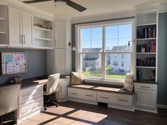 a home office with built - in bookshelves, desk and window seat area