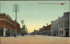 an old postcard with people walking down the street in front of buildings and telephone poles