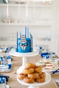 a table topped with donuts covered in blue frosting and a robot mask cake