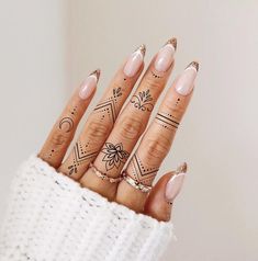 a woman's hand with tattoos on her fingers and fingernails in the shape of arrows