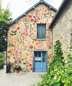 an old building with flowers painted on it's side and a blue door in front