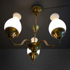 a chandelier with three lights hanging from it's sides in a dark room