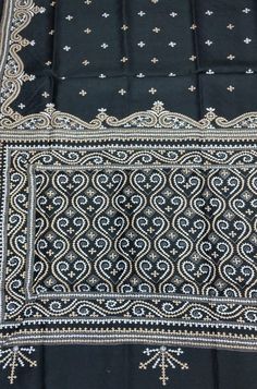 a black and white scarf with an intricate design on the front, sitting on top of a table