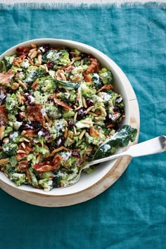 a bowl filled with broccoli, raisins and other toppings on top of a blue table cloth