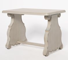 a white wooden table with an ornate design on the top and bottom, sitting against a white background