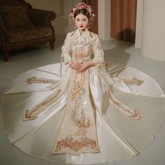 a woman in an elaborate dress sitting on a round rug with her hands clasped to her chest