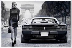 a black and white photo of a woman walking next to a car