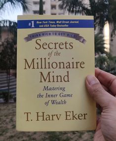 a person holding up a book about the secrets of the millionaire mind by t harry elker