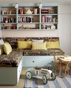 a living room filled with furniture and bookshelves next to a table full of toys