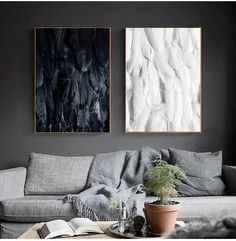 two paintings hanging on the wall above a couch in a living room with a potted plant