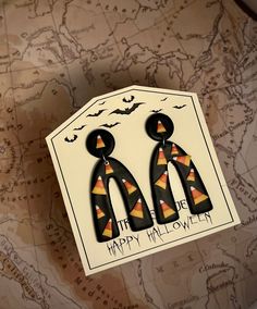 two black and orange earrings on top of a map with the words happy halloween written in it