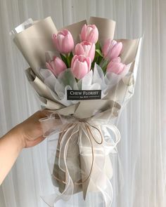 a hand holding a bouquet of pink tulips