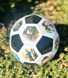 a soccer ball with pictures of people on it in the middle of some green grass