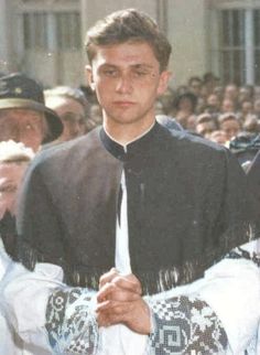 a man wearing a priest's outfit standing in front of a group of people