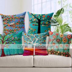 four colorful pillows on a white couch in front of a plant and potted tree