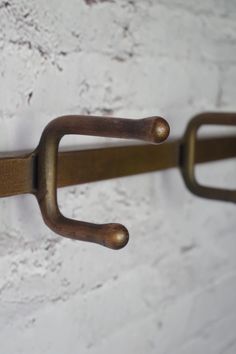 a close up of a metal hook on a white brick wall with rusted handles