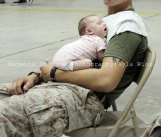 a man holding a baby while sitting in a chair