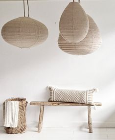 three hanging paper lanterns hang from the ceiling above a bench with two pillows on it