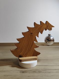 a wooden christmas tree with a silver ornament in the background on a wood floor