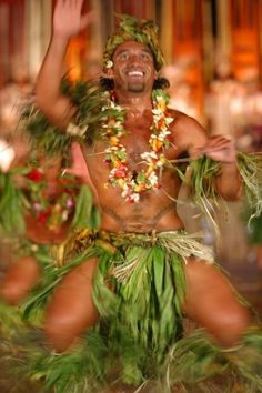 a man in grass hula dancing with other people around him and his hands up