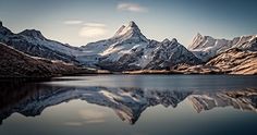 the mountains are reflected in the still water