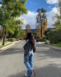 a woman standing in the middle of an empty street with her back to the camera