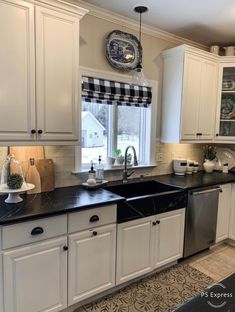 a kitchen with white cabinets and black counter tops