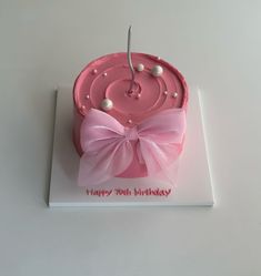 a birthday cake with pink icing and white pearls