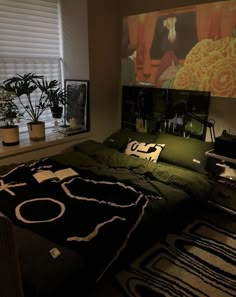 a bed with black and white blankets in a room next to a window, potted plants on the windowsill