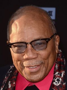 an older man wearing glasses and a red shirt with a skull print scarf around his neck