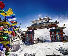 an arch in the middle of a snow covered mountain with flags flying from it's sides