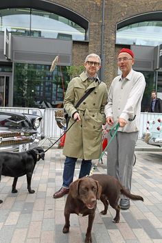 two men walking their dogs on a leash