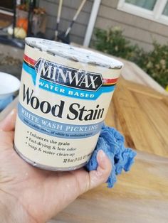 a hand holding a can of wood stain